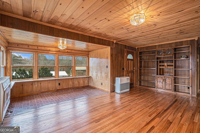 interior space featuring built in shelves, heating unit, wooden ceiling, hardwood / wood-style floors, and wood walls