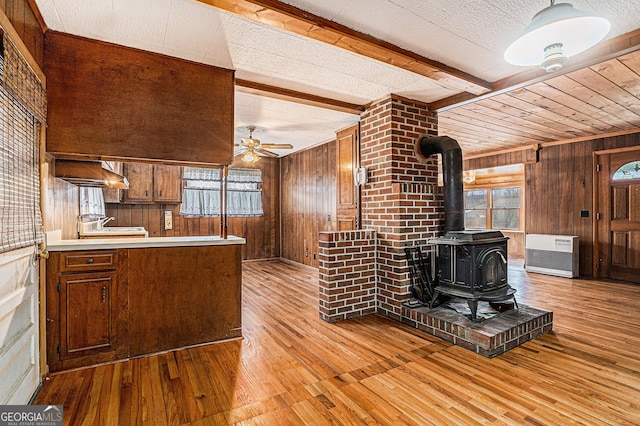 kitchen with a wealth of natural light, ceiling fan, wood walls, and light wood-type flooring