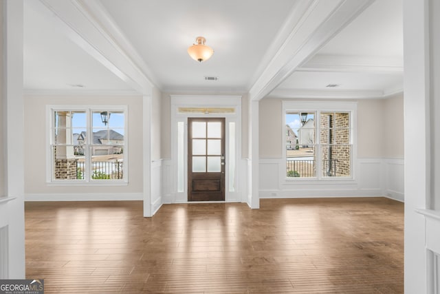 entryway with beam ceiling, crown molding, and wood-type flooring