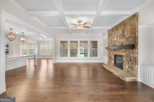 unfurnished living room featuring beam ceiling, coffered ceiling, dark hardwood / wood-style flooring, a fireplace, and ceiling fan with notable chandelier