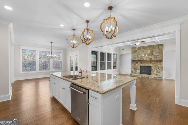 kitchen featuring white cabinetry, sink, stainless steel dishwasher, pendant lighting, and a fireplace