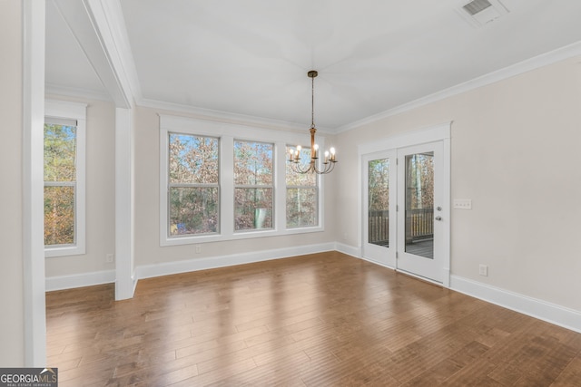 unfurnished dining area featuring hardwood / wood-style floors, an inviting chandelier, and ornamental molding