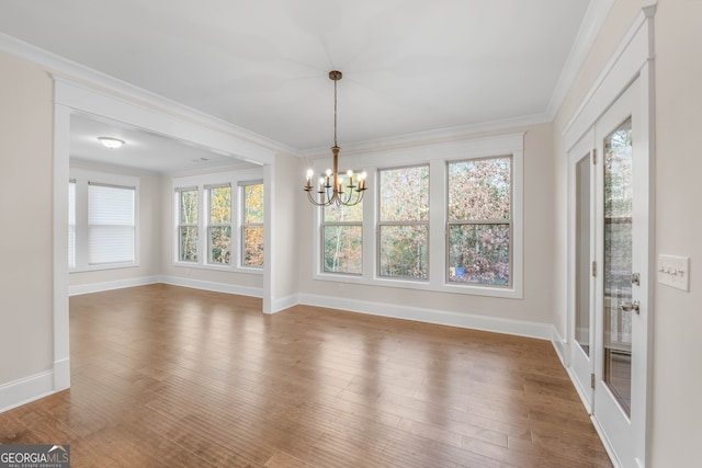 unfurnished dining area with ornamental molding, hardwood / wood-style flooring, and a notable chandelier