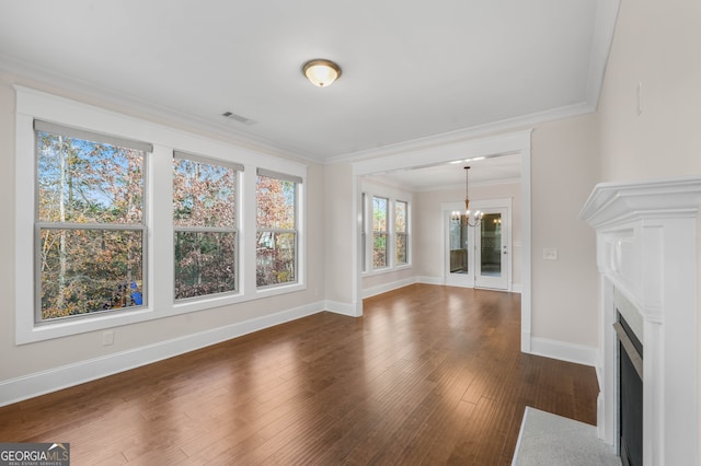 unfurnished living room featuring a chandelier, dark wood-type flooring, and ornamental molding