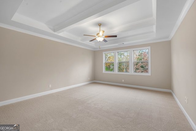 carpeted spare room with a tray ceiling, ceiling fan, and ornamental molding