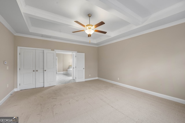 unfurnished bedroom featuring ceiling fan, crown molding, ensuite bathroom, light carpet, and a closet