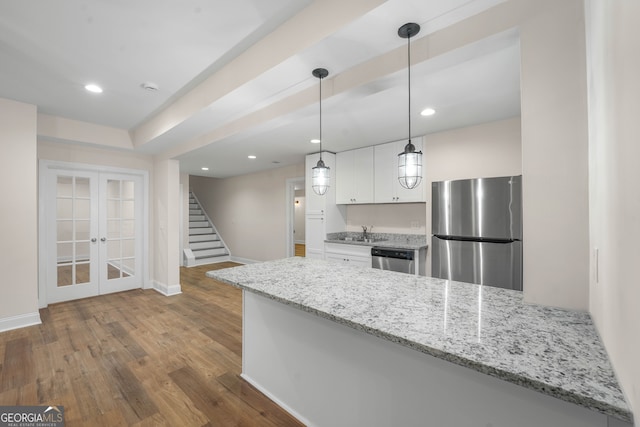 kitchen featuring white cabinetry, light stone counters, kitchen peninsula, pendant lighting, and appliances with stainless steel finishes