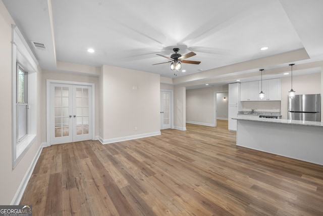 unfurnished living room featuring ceiling fan, french doors, and light wood-type flooring