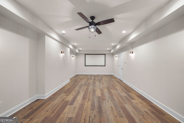 cinema room featuring hardwood / wood-style flooring and ceiling fan