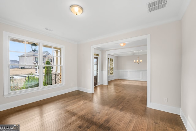 spare room featuring hardwood / wood-style flooring, ornamental molding, and a chandelier