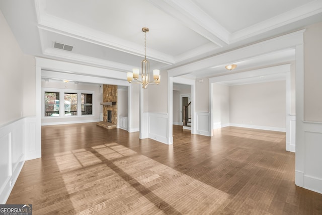 interior space featuring beam ceiling, wood-type flooring, a fireplace, and an inviting chandelier