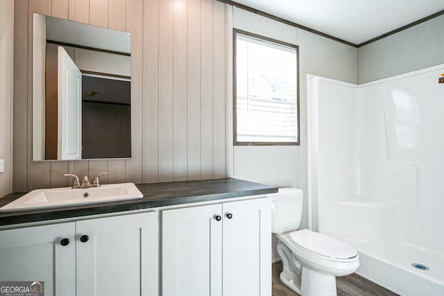 bathroom with walk in shower, vanity, hardwood / wood-style flooring, toilet, and wood walls