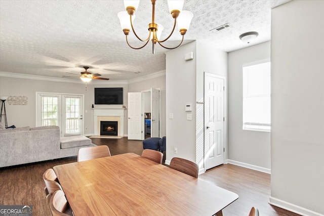 dining room featuring ceiling fan with notable chandelier, dark hardwood / wood-style floors, a textured ceiling, and ornamental molding