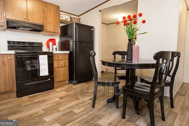 kitchen featuring crown molding, black appliances, and light wood-type flooring