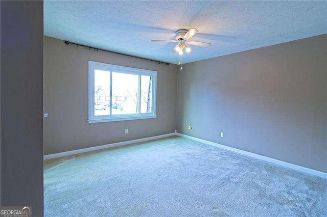 carpeted spare room featuring a textured ceiling and ceiling fan