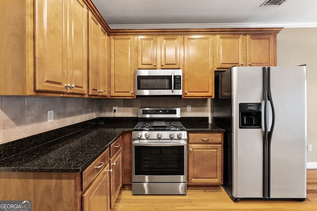 kitchen with decorative backsplash, light wood-type flooring, stainless steel appliances, and dark stone counters