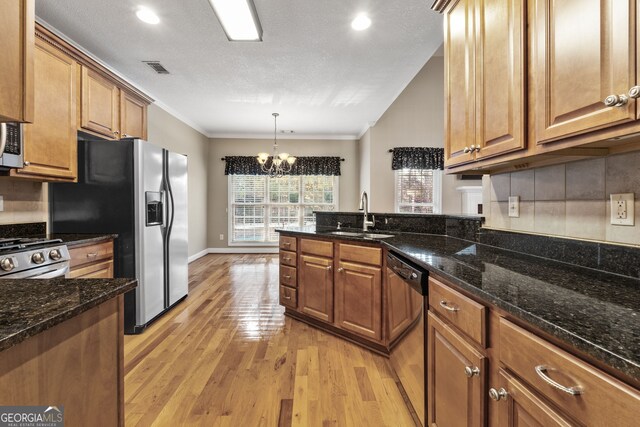 kitchen with an inviting chandelier, sink, light wood-type flooring, a textured ceiling, and appliances with stainless steel finishes