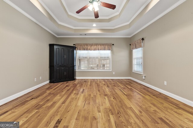 unfurnished bedroom featuring a tray ceiling, ornamental molding, and hardwood / wood-style flooring