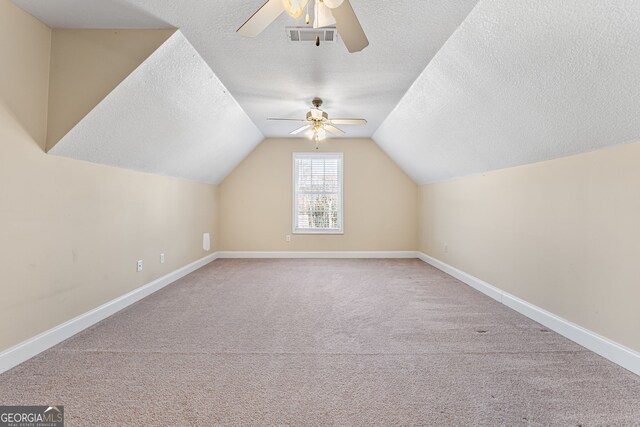 additional living space featuring a textured ceiling, ceiling fan, carpet flooring, and lofted ceiling