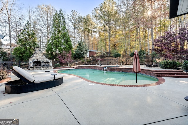 view of swimming pool featuring an outdoor stone fireplace and a patio area