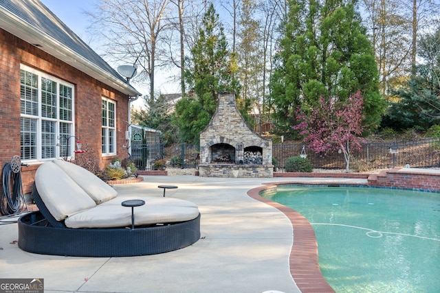 view of pool with an outdoor stone fireplace and a patio