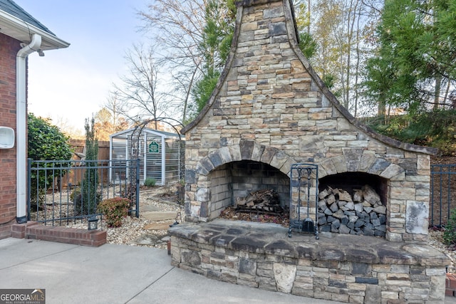 view of patio / terrace with an outbuilding and an outdoor stone fireplace