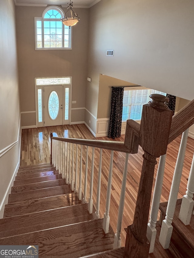 staircase with crown molding and hardwood / wood-style floors