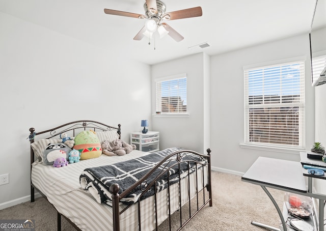 carpeted bedroom featuring multiple windows and ceiling fan