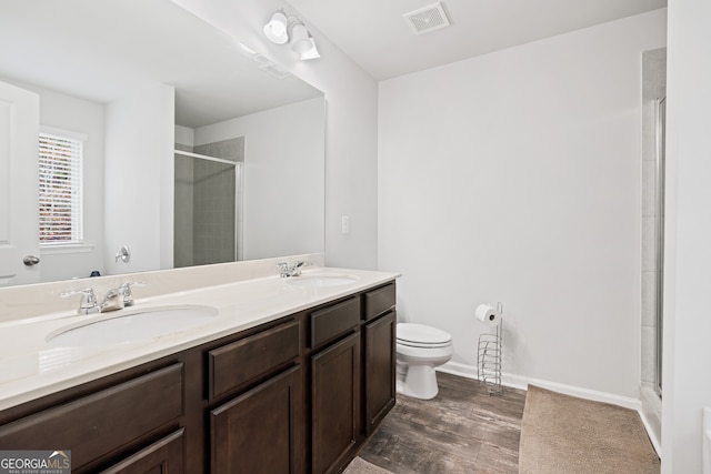 bathroom with hardwood / wood-style floors, vanity, toilet, and a shower with door