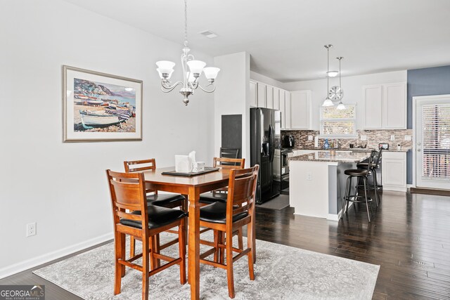 dining room with dark wood-type flooring and a notable chandelier