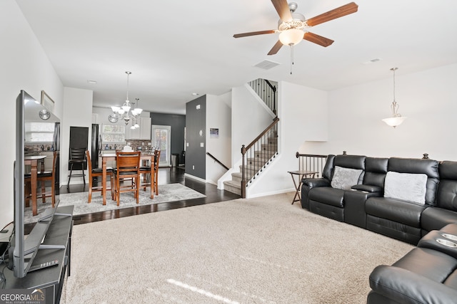 living room with ceiling fan with notable chandelier and dark carpet