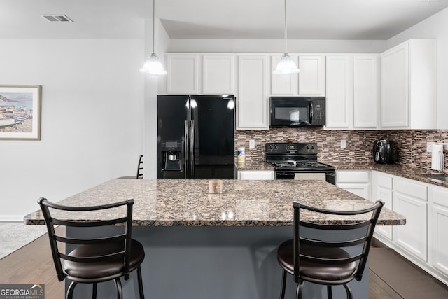 kitchen featuring black appliances, a breakfast bar area, and pendant lighting