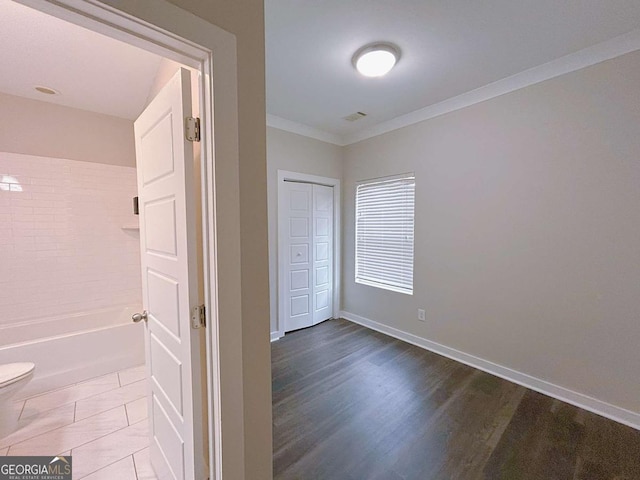 interior space with hardwood / wood-style floors, toilet, and crown molding