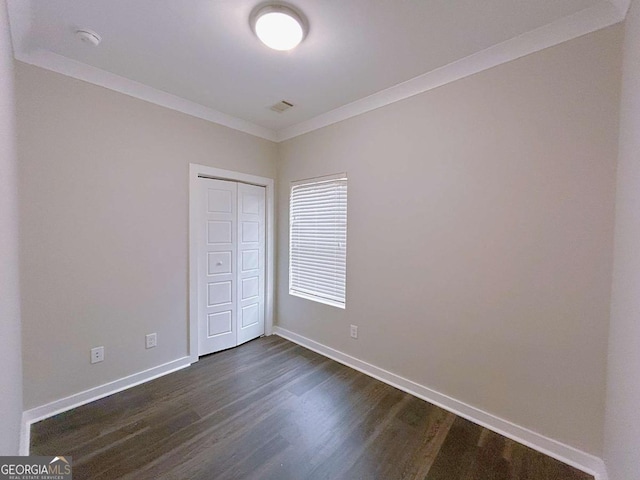 unfurnished bedroom featuring crown molding, a closet, and dark wood-type flooring