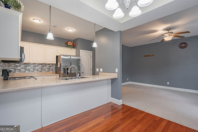 kitchen with sink, hanging light fixtures, backsplash, hardwood / wood-style floors, and black appliances