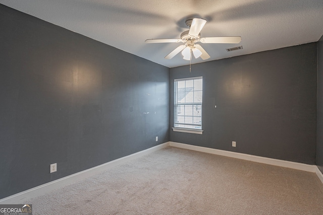 empty room with ceiling fan, carpet floors, and a textured ceiling