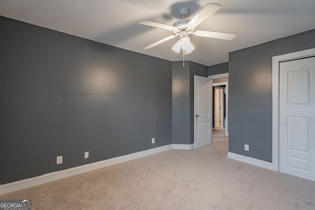 unfurnished bedroom featuring ceiling fan, light colored carpet, and a textured ceiling