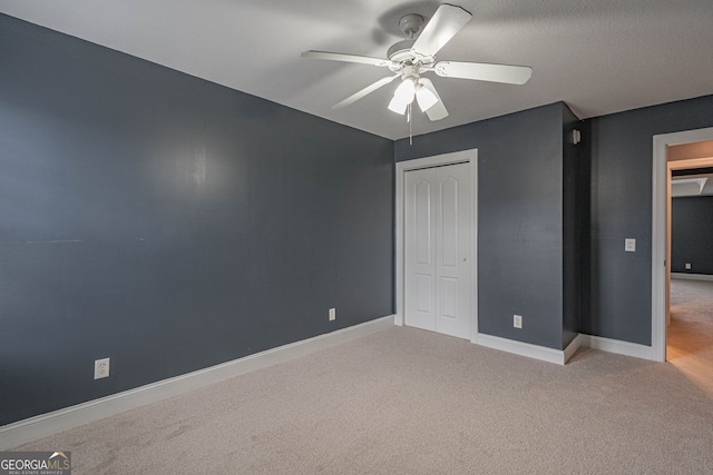 unfurnished bedroom featuring ceiling fan, a closet, and light colored carpet