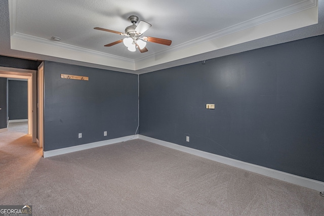 carpeted empty room featuring a raised ceiling, ceiling fan, and ornamental molding