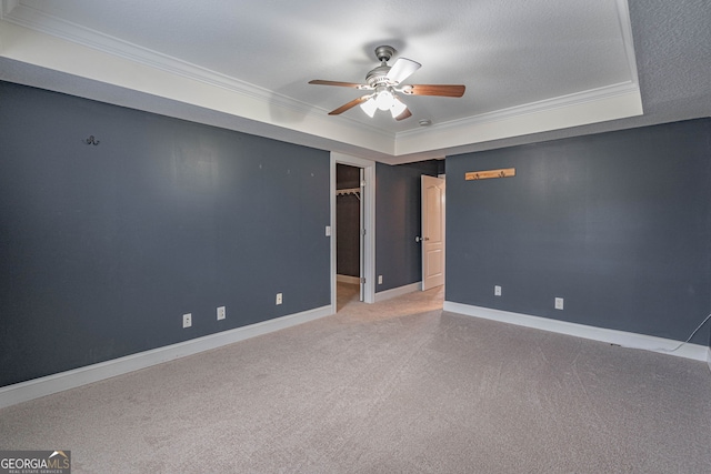 spare room featuring light carpet, a raised ceiling, ceiling fan, ornamental molding, and a textured ceiling