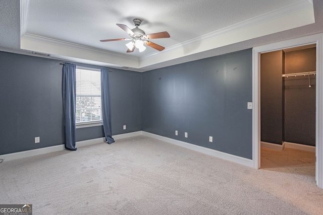 carpeted spare room with a raised ceiling, crown molding, ceiling fan, and a textured ceiling