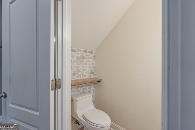 bathroom featuring lofted ceiling and toilet