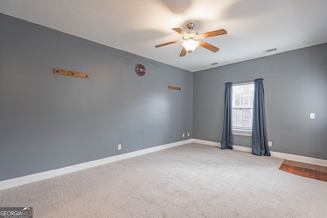 carpeted spare room featuring ceiling fan and a textured ceiling