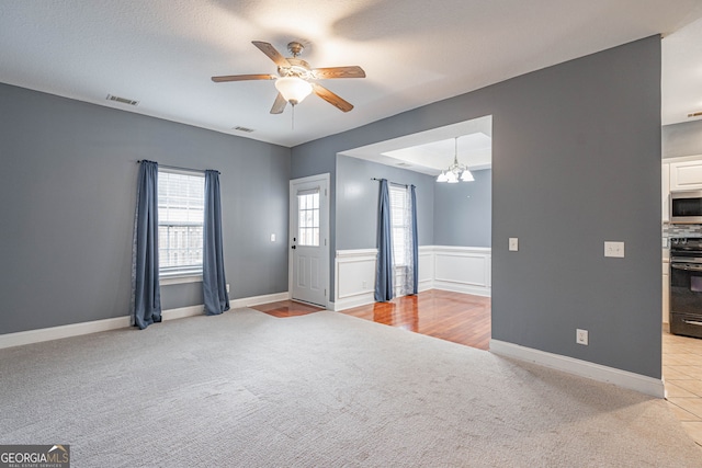 interior space featuring light carpet, a textured ceiling, and ceiling fan with notable chandelier