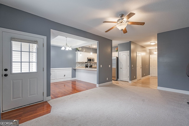 interior space featuring ceiling fan with notable chandelier and light carpet