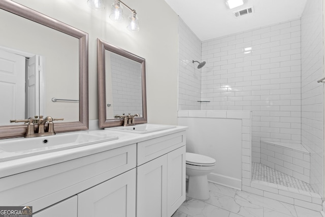 bathroom with vanity, toilet, and tiled shower