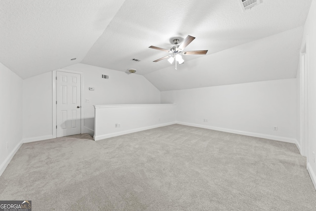 bonus room featuring light colored carpet, a textured ceiling, and vaulted ceiling