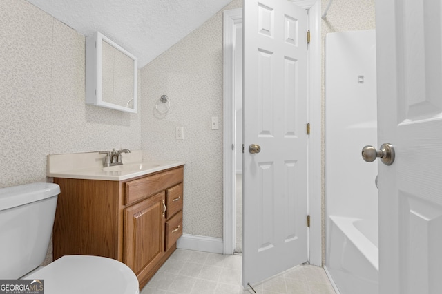 bathroom with vanity, toilet, lofted ceiling, and a textured ceiling