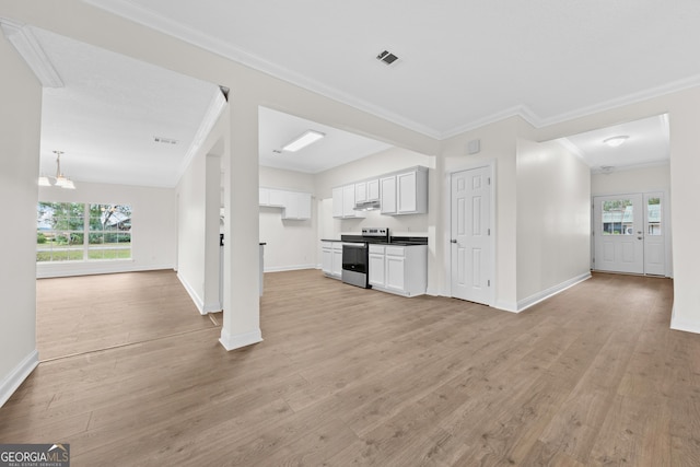 unfurnished living room with an inviting chandelier, light hardwood / wood-style flooring, and crown molding