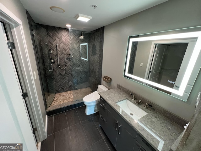 bathroom featuring toilet, a tile shower, and vanity